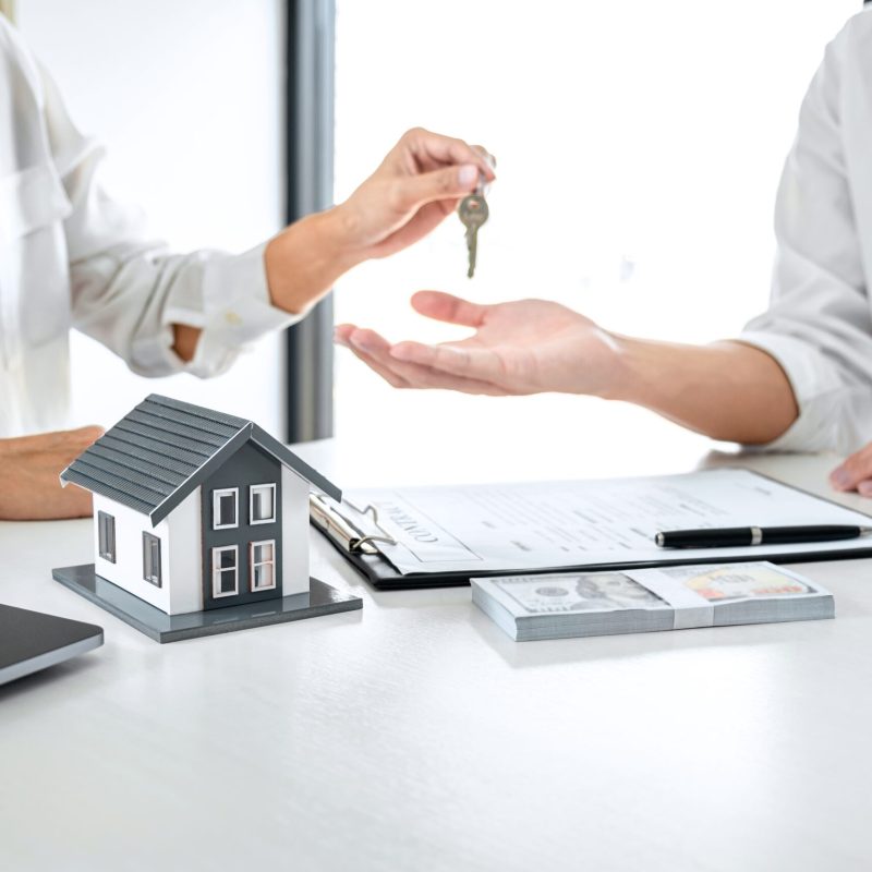 Real estate agent Sales manager holding filing keys to customer after signing rental lease contract of sale purchase agreement, concerning mortgage loan offer for and house insurance.